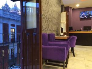 a waiting room with purple chairs and a table at Hotel Leones in Puebla