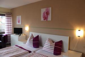 1 dormitorio con 1 cama con almohadas moradas y blancas en Saaletal Pension & Ferienwohnungen, en Bad Bocklet