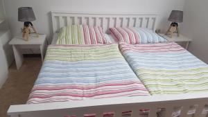 ein Bett mit zwei Kissen und einer gestreiften Decke in der Unterkunft Ferienhaus Lilly am Silbersee in Frielendorf