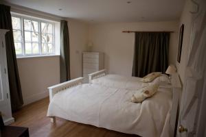 a white bed in a bedroom with a window at Stunning 3 bedroom self catering cottage near Stonehenge, Salisbury, Avebury and Bath All bedrooms ensuite in Pewsey