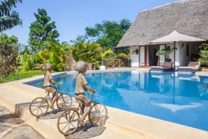 迪亞尼海灘的住宿－Villa Raymond, Diani, Kenya，两座由两只儿童组成的雕像,在游泳池边骑着自行车