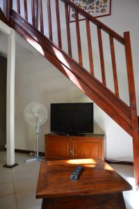 sala de estar con TV y escalera de madera en T3 Duplex Meublé Lagon Réunion, en La Saline-Les-Bains