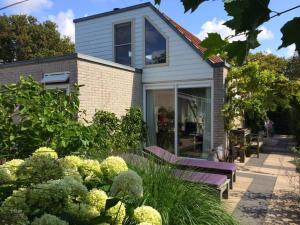 a house with a purple bench in front of a garden at De Kastanje Ouddorp in Ouddorp