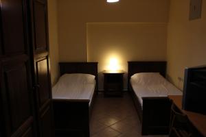 Prenoćište "Magnus" في سلافونسكي برود: غرفة نوم بسريرين ومصباح على طاولة