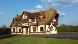 une maison ancienne avec un toit carrelé et de l'herbe dans l'établissement Gîte Les Vignettes, à Bourgeauville