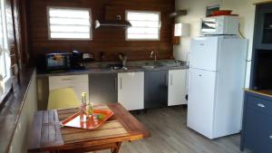 eine Küche mit einem Tisch und einem weißen Kühlschrank in der Unterkunft Gîte Bananier in Bouillante