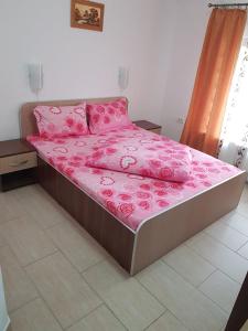 Una cama con sábanas rosas y almohadas rosas. en Onalisa, en Arad