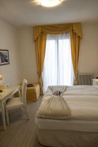 a hotel room with two beds and a desk and a window at Hotel Garni Bel Sito in Tremosine Sul Garda