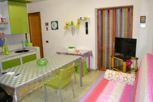 a kitchen with a table and chairs and a tv at Mary&Kate's green house in Scalea