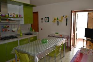 a kitchen with green cabinets and a table with chairs at Mary&Kate's green house in Scalea