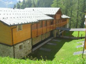 un grande edificio con tetto su un campo verde di Case Vacanze Gli Scoiattoli a Madesimo