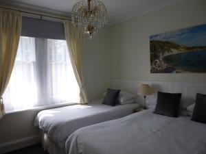 2 camas en un dormitorio con lámpara de araña y ventana en Southernhay Guest House, en Bournemouth
