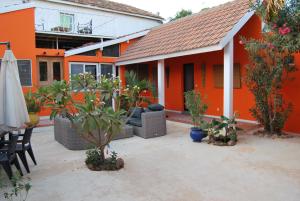 an orange house with a patio with plants and an umbrella at Riad côté jardin in Saly Portudal