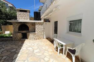 a patio with a stone fireplace and a table and chairs at Apartments Dvorski in Mandre