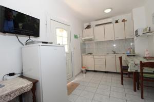 a kitchen with white cabinets and a table and a tv at Apartments Dvorski in Mandre