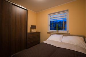 a bedroom with a bed and a window at Domki letniskowe Deluxe in Dąbki