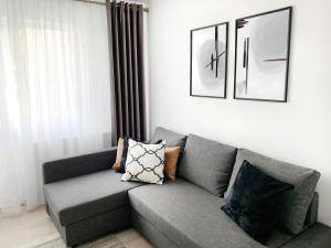a living room with a gray couch with pillows at MHC Quiet Deluxe Suite near Downtown - Free Parking in Braşov