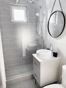 La salle de bains blanche est pourvue d'un lavabo et d'une douche. dans l'établissement MHC Quiet Deluxe Suite near Downtown - Free Parking, à Braşov