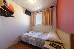 a small bedroom with a bed and a window at Hotel Econômico ao lado do Metrô in São Paulo