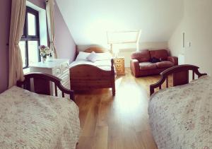a bedroom with two beds and a chair and a couch at The Dairy Lodge in Kilmallock