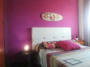 1 dormitorio con pared morada, cama y mesa en El Balcón de Luán, en Suances