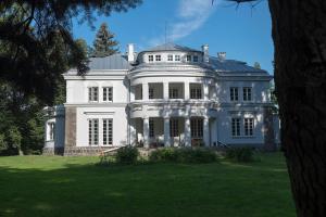 una gran casa blanca en la cima de un exuberante campo verde en Pałac Krzykosy, en Krzykosy