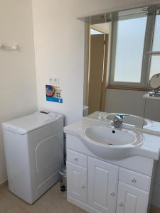 łazienka z umywalką i pralką w obiekcie Appartement cosy proche plage et centre ville w mieście Granville