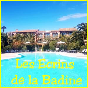une image d'une piscine avec un hôtel en arrière-plan dans l'établissement Les Ecrins de la Badine - hameaux, à Hyères