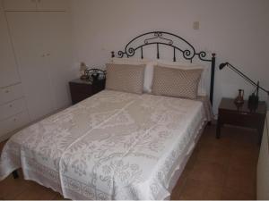 1 dormitorio con 1 cama con edredón blanco en Villa Moschona, en Lakíthra