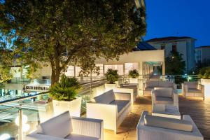 eine Reihe weißer Stühle und ein Baum auf einem Gebäude in der Unterkunft Hotel Gambrinus - Valentini Family Village in Bellaria-Igea Marina