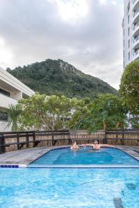 two people in a swimming pool with a mountain in the background at Ocean Retreat 228 in Mount Maunganui