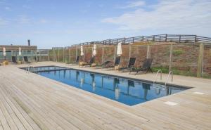 a swimming pool with chairs and a wooden deck at Lodge del Mar in Pichilemu