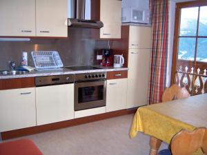 a kitchen with white cabinets and a stove top oven at Appartement zum Rössl in Ramsau am Dachstein