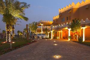 un edificio con una palmera al lado de una entrada en Al Malfa Resort, en Unaizah