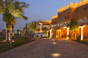 a building with a palm tree next to a driveway at Al Malfa Resort in Unayzah