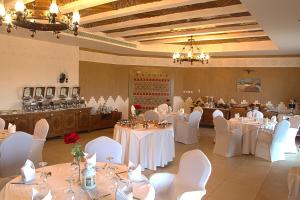 a banquet hall with white tables and white chairs at Al Malfa Resort & Hotel in Unayzah