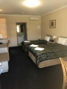
a hotel room with a bed, desk and a lamp at The Bakehouse Motel in Goulburn
