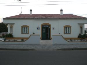 a white house with a black door on a street at Hotel Pulo do Lobo in Serpa