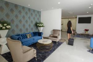 a woman standing in a living room with a blue couch at Hotel Fafense in Fafe