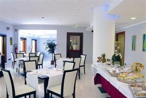 een restaurant met witte tafels en stoelen met eten erop bij Palazzo Foti Hotel in Crotone