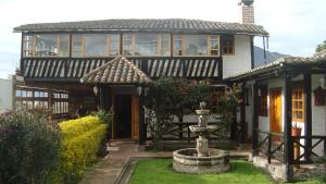 a large house with a porch and a fountain at EL DESCANSO “the Rest” in Otavalo