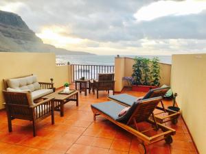 Un balcón con sillas y mesas y vistas al océano. en LivingtheOcean & Big Terrace, en Santa María de Guía de Gran Canaria