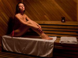 una mujer sentada en una cama en una sauna en Hostería Cumbres Blancas en Esquel