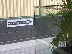 a sign for a walkway to beach on the side of a building at Burleigh Palms Holiday Apartments in Gold Coast