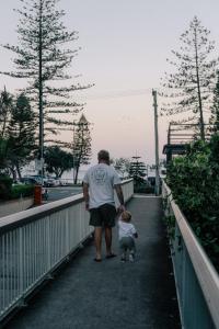un hombre caminando con un niño en un puente en Burleigh Palms Holiday Apartments, en Gold Coast