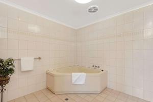 a bath tub in a bathroom with white tiles at Toowoomba Motel & Events Centre in Toowoomba