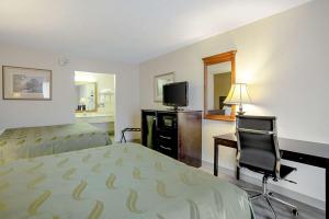 Habitación de hotel con cama, escritorio y TV. en Quality Inn & Suites Live Oak I-10 Exit 283, en Live Oak