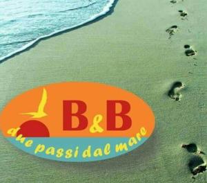 een bord op een strand met voetafdrukken in het zand bij Due Passi dal Mare in Ceriale