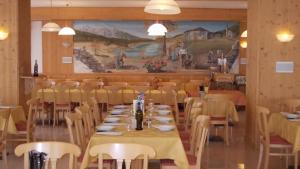 una sala da pranzo con tavoli, sedie e un murale di Hotel Melchiori ad Andalo