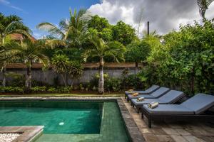 a swimming pool with chaise lounge chairs next to a villa at Villa Surga in Seminyak